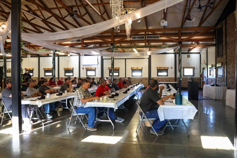 Combine owners seated at long tables in an event hall